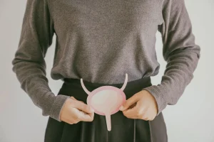 Frau hält sich symbolisch für Blasenschwäche, eine Grafik einer Blase vor ihren Unterbauch.