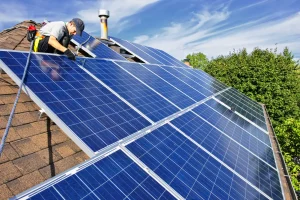 Solarteur montiert Photovoltaikmodule auf einem geneigten Hausdach während der Installation einer PV-Anlage.